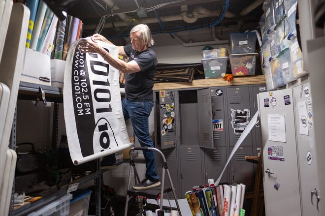 Randy Malloy unfurls an old CD 101 banner found in a closet at radio station WWCD.